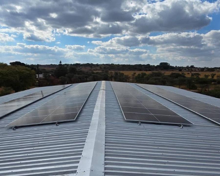 Solar panels on a long corrugated roof under a cloudy sky