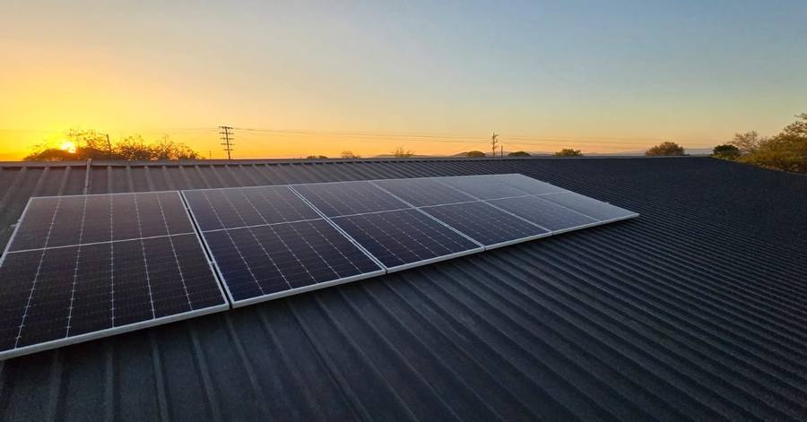 Solar panels on a dark metal roof at sunset