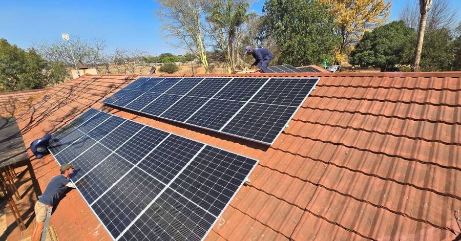 Installers placing panels on a clay-tile roof