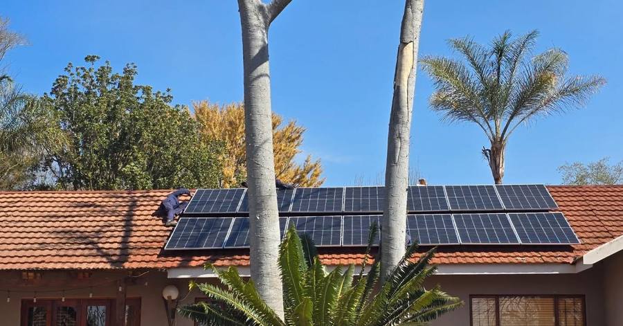 Solar array on a tiled roof behind palm trees